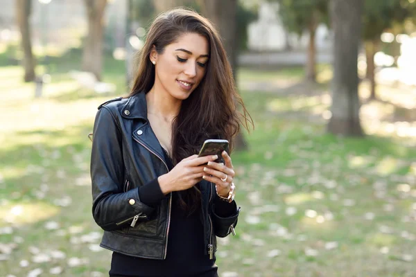 Jonge vrouw met behulp van een smartphone in een stadspark — Stockfoto