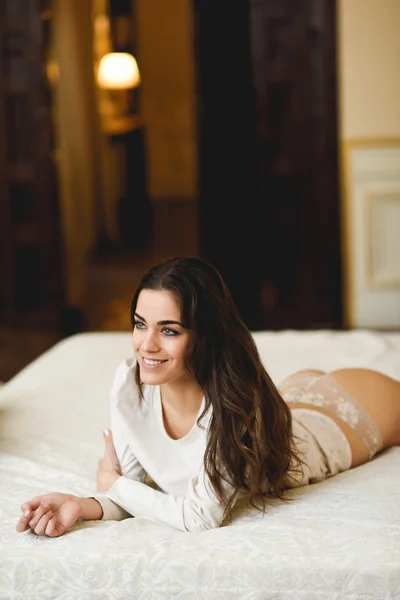 Sexig ung kvinna i underkläder poserar på sängen — Stockfoto