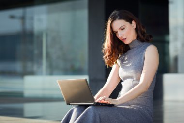 Bir modern ofis yapı içinde onun dizüstü bilgisayar kullanan iş kadını