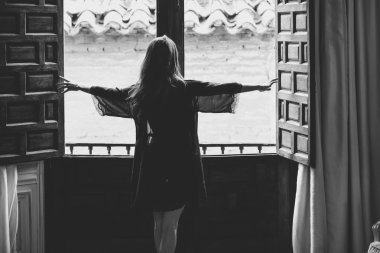 Pencere kenarında iç çamaşırlı seksi genç kadın pozu