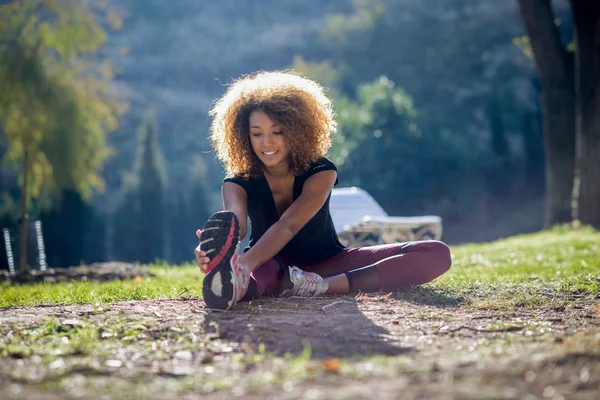 Fitness svart kvinna löpare stretching benen efter att kört — Stockfoto
