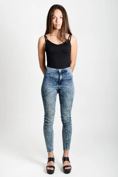 Mladá žena nosí černé tílko a modré džíny — Stock fotografie
