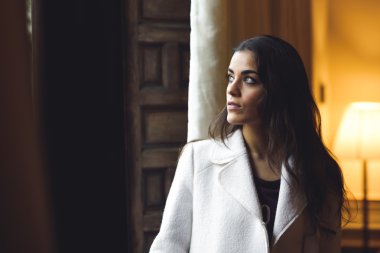 Yatak odasında bir pencere yakınında poz güzel genç kadın