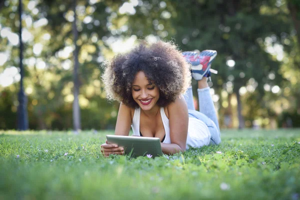 Mulher mista com penteado afro olhando para seu computador tablet — Fotografia de Stock
