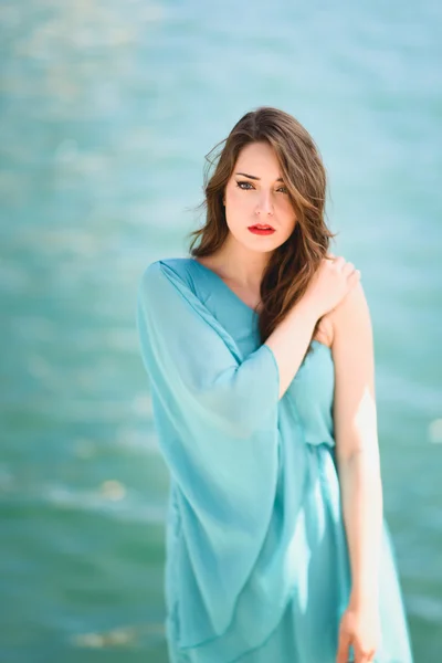 Mujer con ojos azules vistiendo vestido azul en la playa . — Foto de Stock