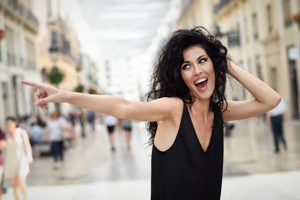 Young woman pointing with her finger in the street — Stock Photo, Image