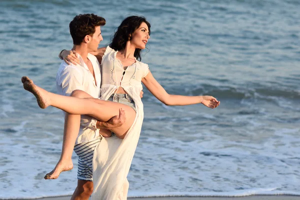 Junges glückliches Paar spaziert an einem schönen Strand — Stockfoto