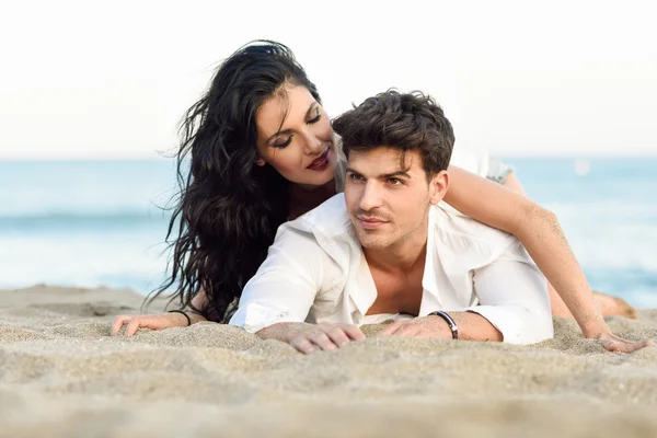 Jovem casal feliz deitado na areia em uma bela praia — Fotografia de Stock