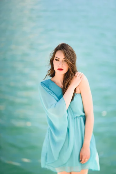 Mujer con ojos azules vistiendo vestido azul en la playa . — Foto de Stock