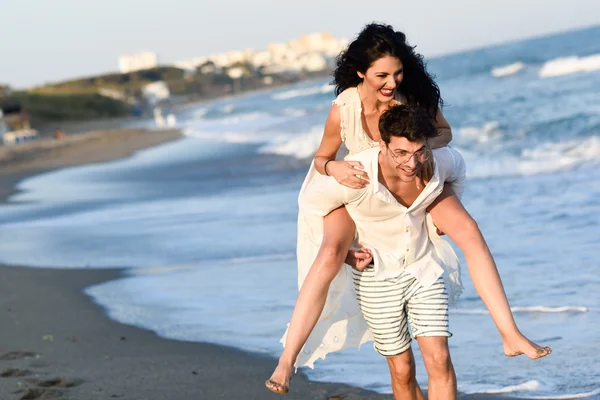 Junges glückliches Paar spaziert an einem schönen Strand — Stockfoto