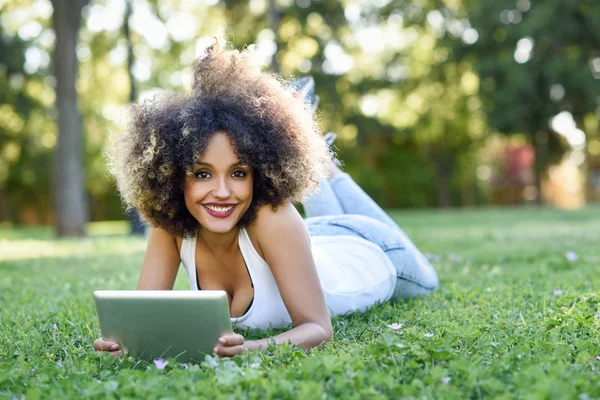 Mixed woman with afro hairstyle looking at her tablet computer — Stock Photo, Image