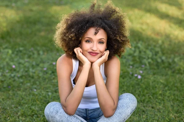 Mladá Černoška s afro účesem sedět v městském parku — Stock fotografie