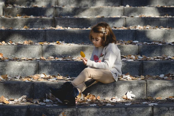 Menina brincando em um parque da cidade no outono — Fotografia de Stock