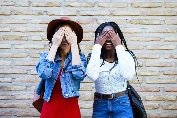 Dos amigas cubriéndose los ojos al aire libre. Mujeres multiétnicas. — Foto de Stock