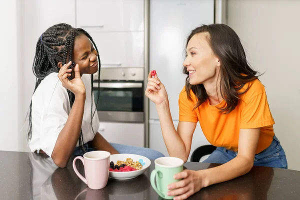 Twee vrienden die een gezonde snack eten terwijl ze thuis chatten — Stockfoto