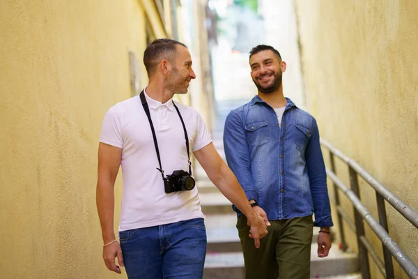 Пара геев-туристов, идущих рука об руку по улице. — стоковое фото