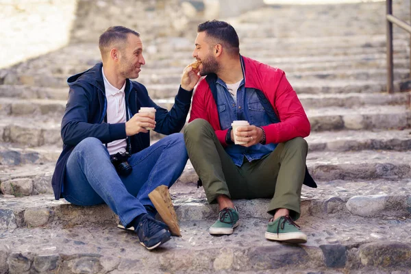 Gay couple having a take-out meal on the street — Stock Photo, Image