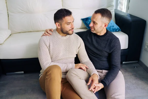 Homosexuell pärchen sitzen in der nähe von die couch bei zuhause im ein romantisch moment — Stockfoto