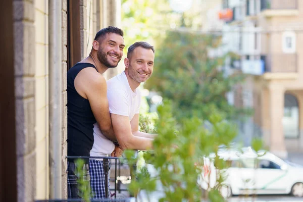 Homosexuella par i ett romantiskt ögonblick lutar sig ut från sin balkong. — Stockfoto