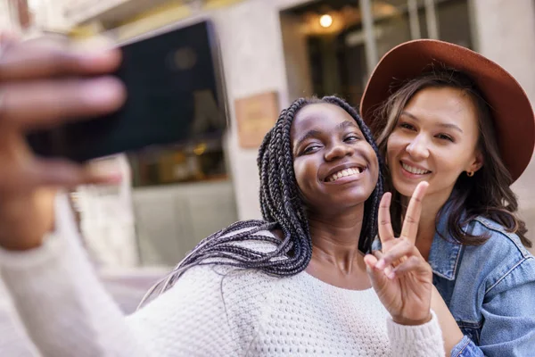 Dos hermosas mujeres multiétnicas haciendo selfie y muecas —  Fotos de Stock