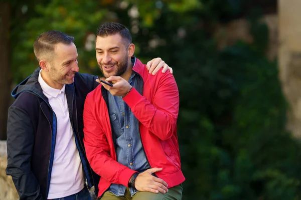 Пара геев вместе записывают голосовую запись на свой смартфон. — стоковое фото