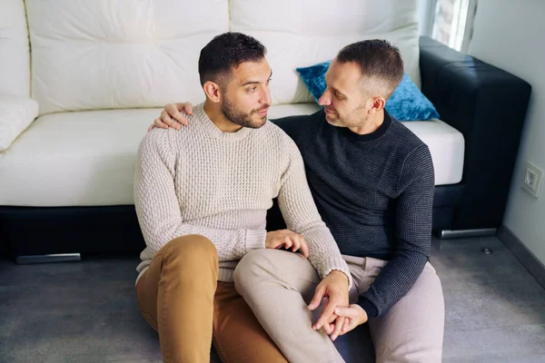 Gay couple sitting near the couch at home in a romantic moment — Stock Photo, Image