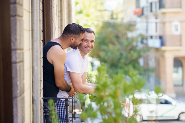 Gay couple in a romantic moment leaning out of their balcony. — Stock Photo, Image