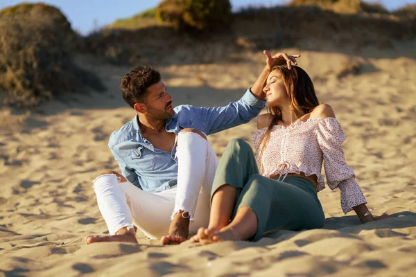 Atractiva pareja sentada en la arena de la playa — Foto de Stock