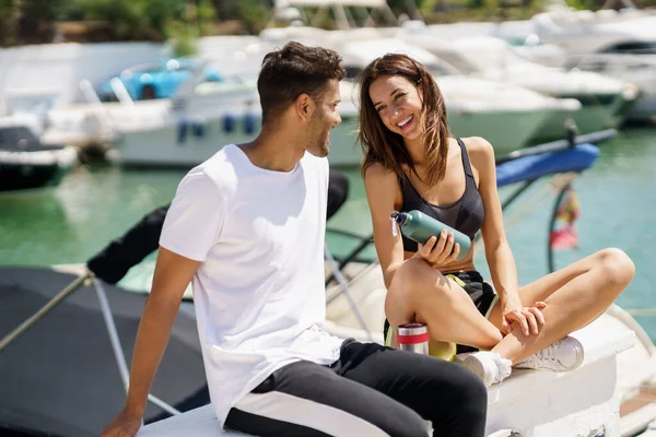 Jeune couple sportif s'hydrater avec de l'eau dans des canettes en métal tout en faisant une pause après le sport. — Photo