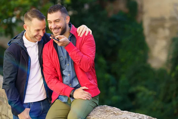 Gay pár nahrávat hlasový vzkaz společně na svém smartphonu. — Stock fotografie