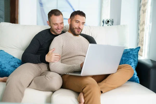 Pareja gay consultando sus planes de viaje junto con un portátil. —  Fotos de Stock