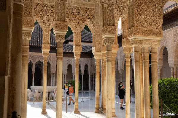 Touristen mit Masken besuchen den Patio de los Leones der Alhambra in Granada. — Stockfoto