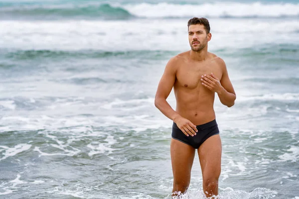 Przystojny muskularny mężczyzna kąpiący się na plaży — Zdjęcie stockowe