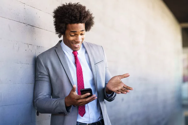 Black Businessman using a smartphone near an office building — Stock Photo, Image