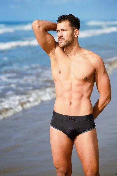 Młody sportowiec z ciałem fitness stojącym na plaży — Zdjęcie stockowe