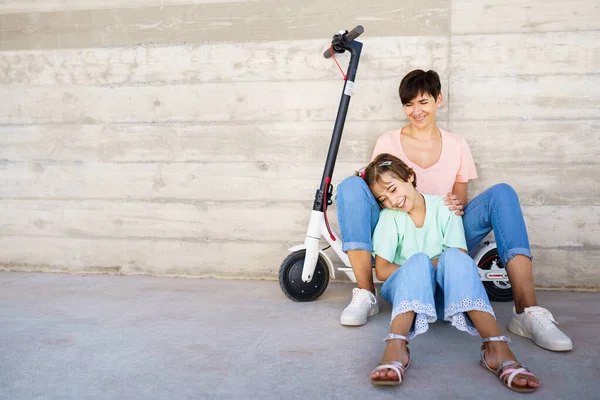 Mãe e filha sentadas em uma scooter elétrica — Fotografia de Stock