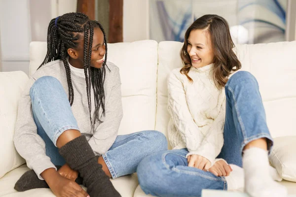 Deux amies étudiantes souriant ensemble sur le canapé à la maison. — Photo