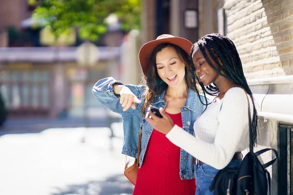 两个朋友在一起看他们的智能手机。多族裔妇女. — 图库照片