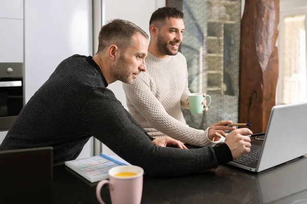 Couple gay travaillant ensemble à la maison avec leurs ordinateurs portables. — Photo