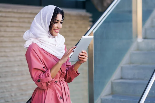 Νεαρή μουσουλμάνα γυναίκα φοράει μαντίλα χρησιμοποιώντας ψηφιακή ταμπλέτα σε εξωτερικούς χώρους — Φωτογραφία Αρχείου