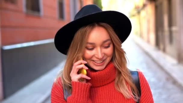 Blond vrouw praten op haar smartphone tijdens het lopen in de straat. — Stockvideo