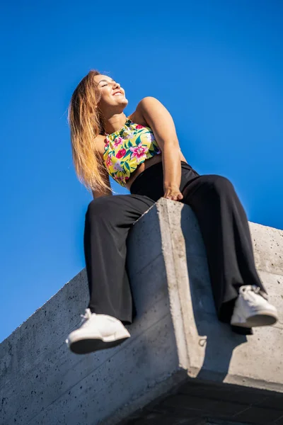 Забавная юная девушка сидит на городской стене — стоковое фото