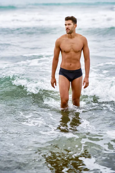 Przystojny muskularny mężczyzna kąpiący się na plaży — Zdjęcie stockowe