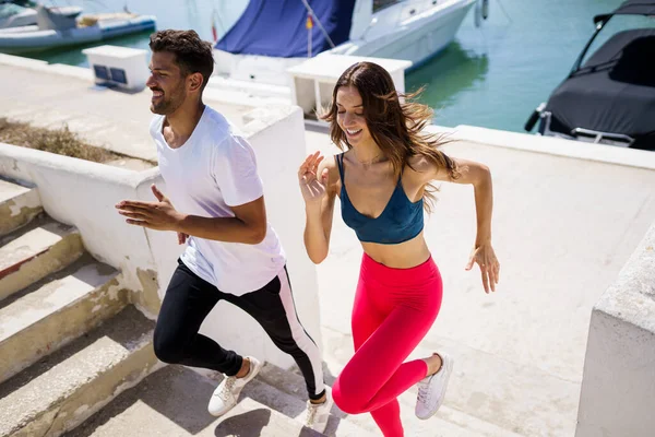Sportliches Paar trainiert hart, indem es gemeinsam im Freien Treppen hochläuft. — Stockfoto
