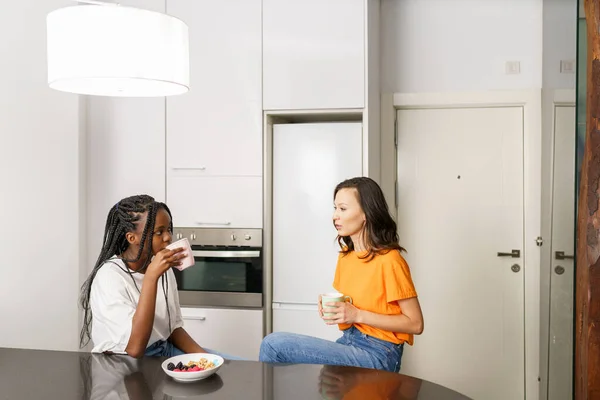 Två vänner som tar ett hälsosamt mellanmål medan de småpratar hemma — Stockfoto