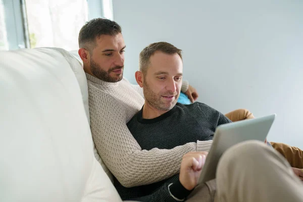 Homosexuella par konsulterar sina reseplaner tillsammans med en digital surfplatta. — Stockfoto