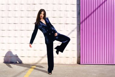 Pembe panjurun yanında poz veren mavi elbiseli bir kadın..