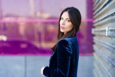 Modern bir binanın yanında mavi takım elbiseli bir kadın poz veriyor..