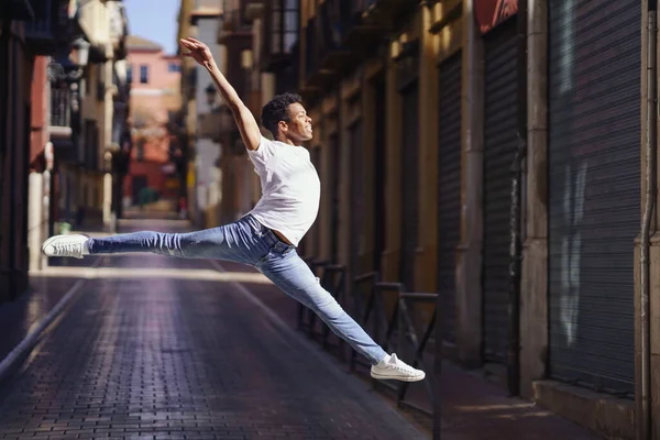 Glücklicher schwarzer Kerl macht einen akrobatischen Sprung mitten auf der Straße. — Stockfoto