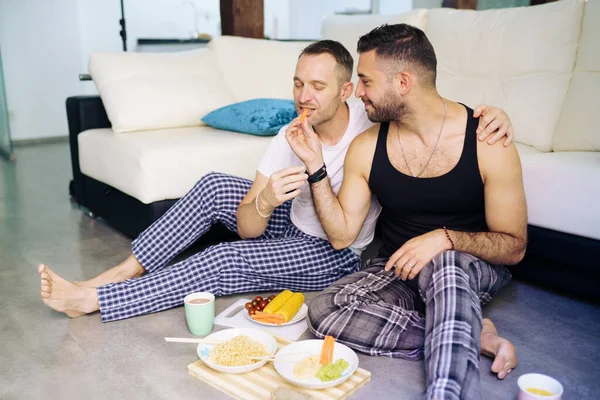 Couple gay manger ensemble assis sur leur salon étage. — Photo